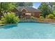 Backyard swimming pool with stone accents, patio, outdoor dining, mature landscaping, offering a private oasis at 1310 Weddington Hills Dr, Matthews, NC 28104