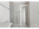 Modern shower with glass door, neutral tiling, and built-in niche for bath products at 15034 Scoter St, Charlotte, NC 28262