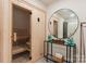 Relaxing sauna room featuring light wood paneling, a glass door, and a modern console table with a round mirror at 15037 June Washam Rd, Davidson, NC 28036