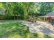 Private back patio featuring a stone picnic table, an umbrella, and a spacious lawn area at 220 Blackberry Trl, Concord, NC 28027
