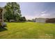 Large, grassy backyard features a versatile metal garage and a charming wooden playset for outdoor fun at 233 Reliance Rd, Kings Mountain, NC 28086