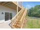 Exterior backyard view featuring wooden stairs leading to a balcony, a glass sliding door, and a well-maintained lawn at 24578 Blue Heron Cir # 407, Lancaster, SC 29720