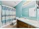 Blue bathroom with a shower-tub combo, decorative shower curtain, vanity, and a large mirror at 328 Pamela St, Gastonia, NC 28054