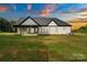 Exterior of home, displaying white siding, black trim, and a well-manicured lawn against a sunset sky at 5015 Lancaster Hwy, Monroe, NC 28112