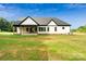 Rear exterior view of a modern farmhouse featuring white siding, black trim, and a spacious green lawn at 5015 Lancaster Hwy, Monroe, NC 28112