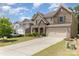 Suburban home exterior featuring a stone and brick facade, well-maintained lawn, and a paved driveway leading to a two-car garage at 5098 Burnwald Ct, Fort Mill, SC 29715