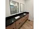Bathroom featuring a double sink vanity with black countertop, wooden cabinets and square mirrors at 908 Apex Dr, Albemarle, NC 28001
