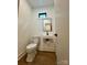 Well-lit powder room featuring contemporary fixtures, a floating sink, and wood-look flooring at 908 Apex Dr, Albemarle, NC 28001