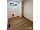 Neutral laundry room featuring wood-look floors, built-in shelving, and a small window at 908 Apex Dr, Albemarle, NC 28001