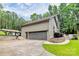 View of a large garage with a stone facade, wooden fence and well-maintained lawn at 9423 Man O War Rd, Fort Mill, SC 29707