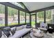 Enclosed sun room with floor-to-ceiling windows, a comfortable daybed, and scenic views of the landscaped backyard at 9423 Man O War Rd, Fort Mill, SC 29707