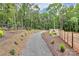 Gravel walking path winds through landscaped backyard with mature trees and privacy fencing, for peaceful strolls at 9423 Man O War Rd, Fort Mill, SC 29707
