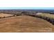 Wide aerial shot of land with a road, showing a mix of fields, woods, and the property's potential at 0000 Milling Rd, Rock Hill, SC 29730