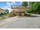Two-story home featuring a large carport, storage units and exterior stairs leading to the upper wooden deck at 111 Trails End Ln, New London, NC 28127