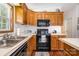 Galley style kitchen features black appliances, wooden cabinets, and ample countertop space at 111 Trails End Ln, New London, NC 28127