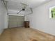 A simple garage space with a closed gray door, light colored walls, and a single window at 1123 Timberlane Dr, Lincolnton, NC 28092
