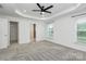 A bright bedroom features a tray ceiling, ceiling fan, and large windows overlooking the yard at 13022 Rover St, Charlotte, NC 28273
