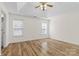 Spacious main bedroom with wood-look floors, tray ceiling, ceiling fan, and large windows at 131 Canopy Ct, Mooresville, NC 28115