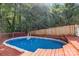 Backyard pool with wooden deck, privacy fence and mature trees offers a tranquil oasis for relaxation and recreation at 131 Canopy Ct, Mooresville, NC 28115