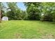 Spacious backyard with lush lawn and mature trees offers a serene outdoor space, complete with a storage shed at 1512 Anthony Dr, Gastonia, NC 28052