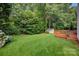 A large, well-maintained backyard with lush green grass, mature trees, a shed, and a wooden deck at 16013 Wynfield Creek Pkwy, Huntersville, NC 28078