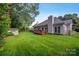 A spacious backyard featuring a well-maintained lawn, mature trees, a storage shed, and a charming wooden deck at 16013 Wynfield Creek Pkwy, Huntersville, NC 28078