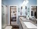 Bright bathroom featuring double sinks, granite countertops, and a glass door shower, connected to the primary bedroom at 17438 Purser Dr, Locust, NC 28097
