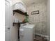 Functional laundry room with a modern washer and dryer, decorative shelving, and brick accent wall at 17438 Purser Dr, Locust, NC 28097