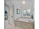 Elegant bathroom showcasing a soaking tub beneath a stained glass window and chandelier lighting at 19506 Mary Ardrey Cir, Cornelius, NC 28031