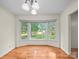 Sunlit dining area with hardwood floors and large bay windows overlooking the yard, creating a cozy atmosphere at 2831 Puetts Chapel Rd, Bessemer City, NC 28016