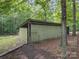 View of the rear of a property showing a pale yellow outbuilding with fencing and surrounding foliage at 2831 Puetts Chapel Rd, Bessemer City, NC 28016