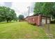 View of a brick home with a detached garage and a spacious, well-maintained green backyard with mature trees at 2836 20Th Street Ne Ln, Hickory, NC 28601