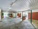 Interior of horse stable with individual stalls, brick pillars, red doors, and overhead lighting at 355 Pelham Ln, Mooresville, NC 28115
