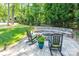 Outdoor fire pit area with built-in stone seating, surrounded by lush greenery and mature trees at 4017 Halyard Dr, Denver, NC 28037