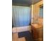 Blue bathroom with a shower/tub combo, tile walls, and a small sink with a wooden vanity at 408 Moose St, Albemarle, NC 28001