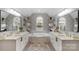 Bright bathroom featuring dual vanities, a soaking tub under an arched window, and stylish wallpaper at 7800 Conifer Cir, Indian Trail, NC 28079