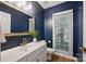 Stylish half bathroom featuring modern vanity, a decorative mirror, and navy blue accent walls at 8805 Deerland Ct, Huntersville, NC 28078
