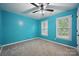 Bright bedroom featuring two windows, a ceiling fan, blue paint and neutral carpet at 8805 Deerland Ct, Huntersville, NC 28078
