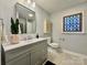 Well-lit bathroom with gray vanity, decorative window, neutral color palette, and modern fixtures at 9305 Harps Mill Ct, Charlotte, NC 28270