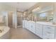 Bright bathroom featuring double vanity, large mirror, soaking tub, and glass-enclosed shower at 11313 Limehurst Pl, Charlotte, NC 28278