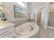 Bathroom featuring white soaking tub, white vanity, tile accents, and an elegant pier painting at 11313 Limehurst Pl, Charlotte, NC 28278