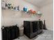 Functional laundry room with modern washer and dryer units and ample shelving for storage and organization at 11313 Limehurst Pl, Charlotte, NC 28278