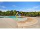 Community pool with a splash pad area and plenty of seating, surrounded by lush greenery at 11313 Limehurst Pl, Charlotte, NC 28278