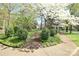 Landscaped front yard showcases mature trees, flowering bushes, and a well-maintained lawn at 1137 Queens W Rd, Charlotte, NC 28207