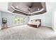 Spacious primary bedroom with tray ceiling, large windows, and plush carpeting at 12002 Cobham Ct, Huntersville, NC 28078