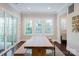 Dining area with a long wooden table, natural light from large windows, and a view of the backyard at 15103 Cimarron Hills Ln, Charlotte, NC 28278