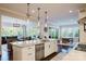 Modern kitchen island with stainless steel appliances and lighting fixtures, transitioning into living room and dining areas at 15103 Cimarron Hills Ln, Charlotte, NC 28278