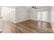 Bright, empty living room with wood-look flooring, ceiling fan, and double doors to balcony at 16344 Redstone Mountain Ln, Charlotte, NC 28277