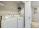 Bright laundry room with white washer and dryer units, overhead shelving and access door to an adjacent space at 2614 Ocracoke St, Charlotte, NC 28208