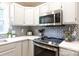 Updated kitchen featuring white cabinets, stainless steel appliances, modern backsplash, and stylish countertops at 27092 Village Dr, Fort Mill, SC 29708